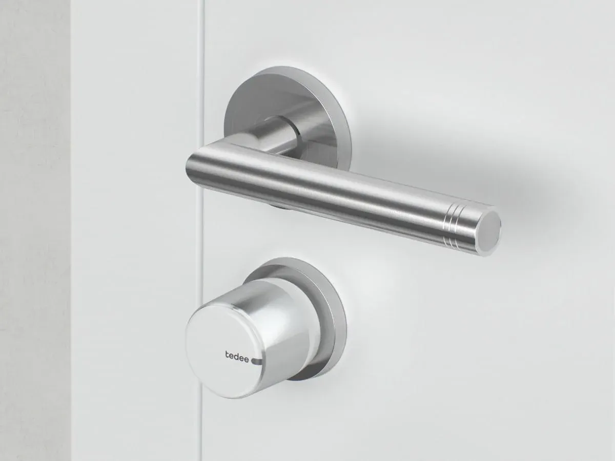 Tedee Go 2 posé sous la poignée d'une porte blanche, côté intérieur